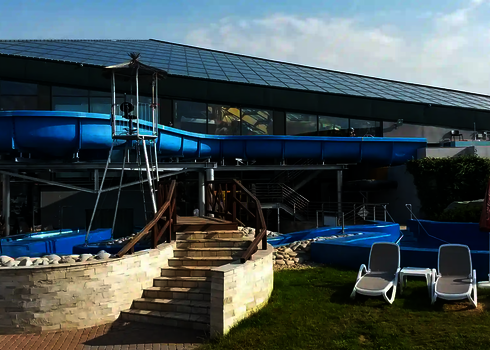 Übersicht des Wildwasserflusses im Außenbereich eines Erlebnisbads mit Liegestühlen im Vordergrund.