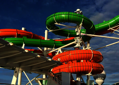 Eine grüne und eine orangene Röhrenrutsche an Deck eines Kreuzfahrtschiffes.