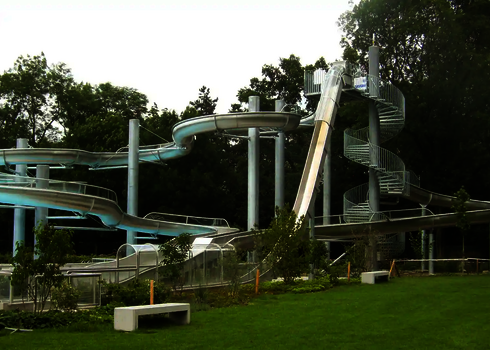 Freifall und WR1040 Wasserrutsche aus Edelstahl in grüner Freibadumgebung.