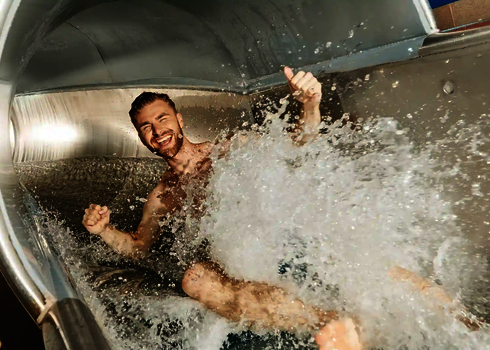 Ein lachender Mann der sich im Wasserschwall einer RR1200 Wasserrutsche befindet.