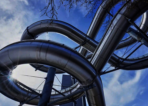 Blick von unten auf eine kurvige Edelstahl Wasserrutsche unter freiem Himmel.