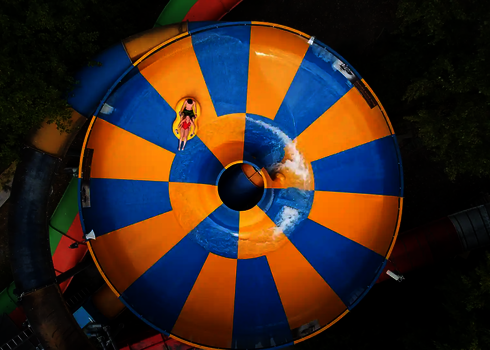 Vogelperspektive auf eine Raft Bowl Wasserrutsche, in der sich zwei Personen auf einem Rutschreifen befinden.