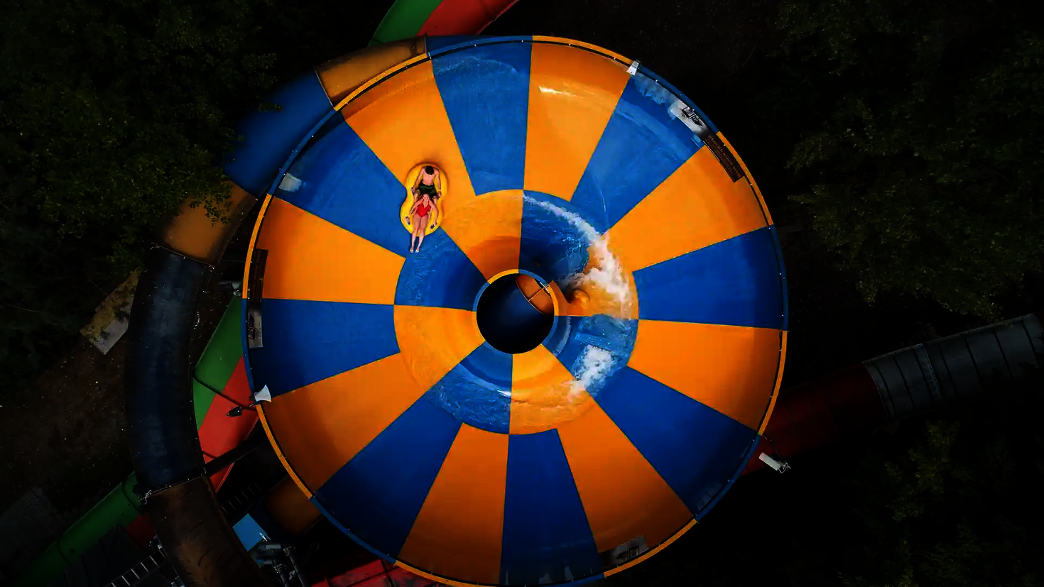 Vogelperspektive auf eine Raft Bowl Wasserrutsche, in der sich zwei Personen auf einem Rutschreifen befinden.
