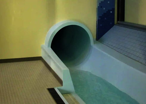 Innenaufnahme zeigt Rutschenauslauf einer hellen Wasserrutsche im Schwimmbad.