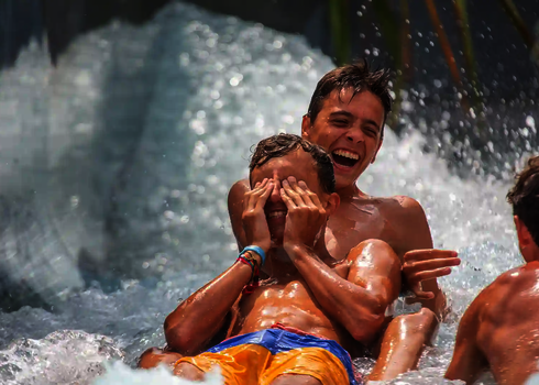 Mehrere Kinder rutschen lachend durch eine Wildwasserfluss-Wasserrutsche.