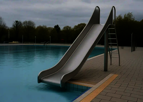 Eine Edelstahl-Kastenrutsche mit Leiter endet direkt am Beckenrand eines Freibads.