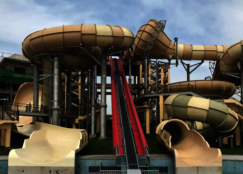 Red conveyor track for slide rafts leads steeply upwards between large tube slides.