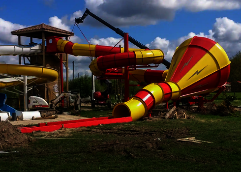 Aufbau einer roten Trichterrutsche im Wasserpark mit Kran und Turm.