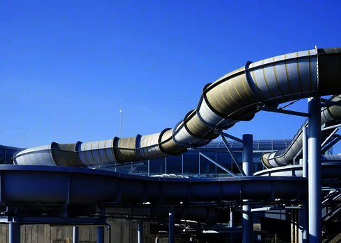 Blick auf geschwungene Wasserrutschen, außerhalb eines Glasgebäudes.