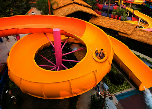 Blick von oben auf eine kreisförmige gelbe RR2700 Rutsche in einem Wasserpark.