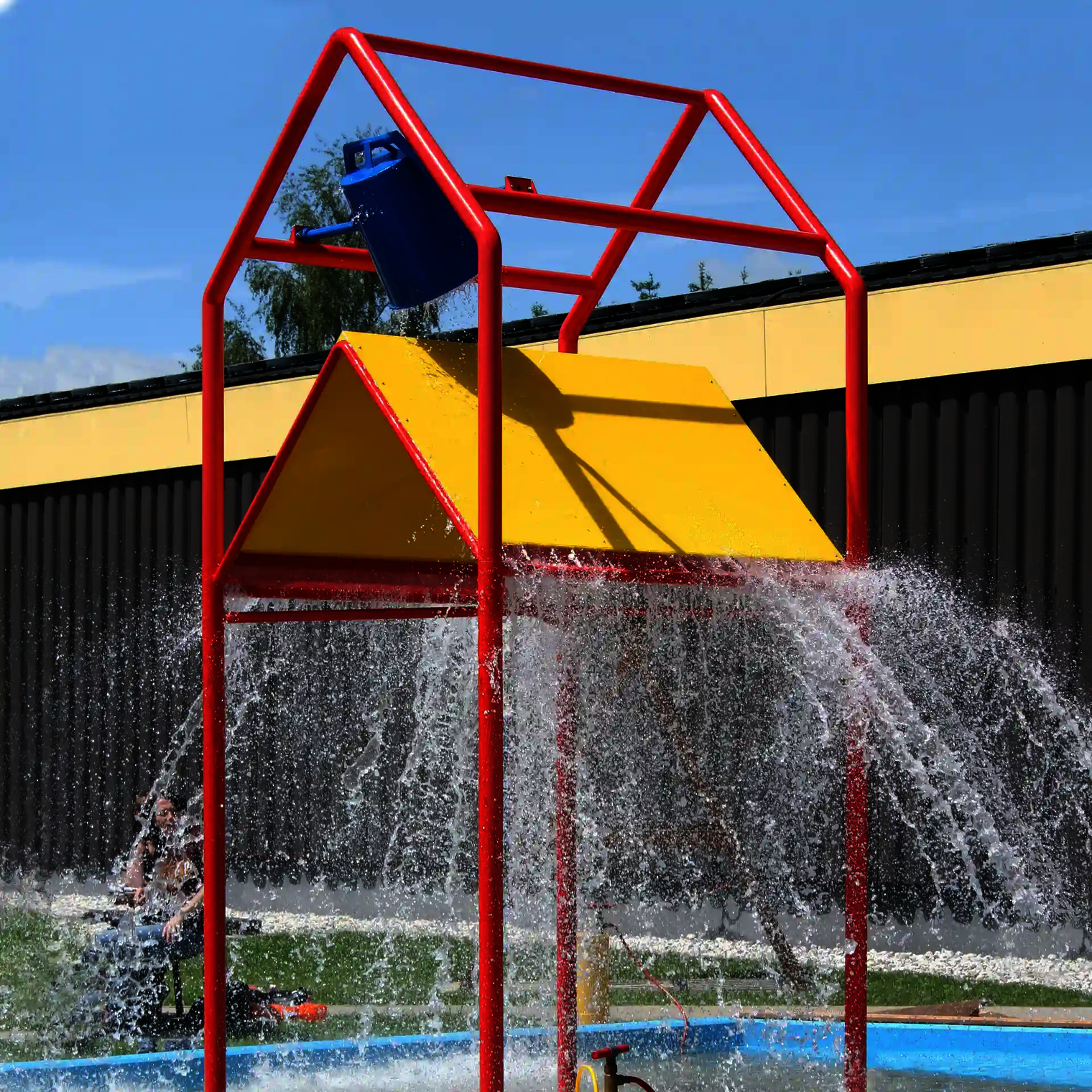 Gelb-Rotes Wie-Spray Element "Strandhaus" mit spritzendem wasser.