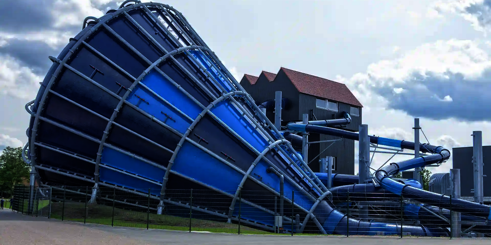 Großer Cyclone-Trichter in Blau mit angrenzender Röhrenrutsche vor modernem Rutschenturm.