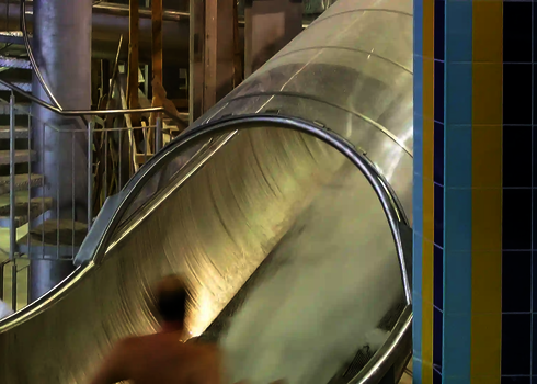 Ein Badegast rutscht durch den geschlossenen Speed Blaster im Innenbereich eines Hallenbades.