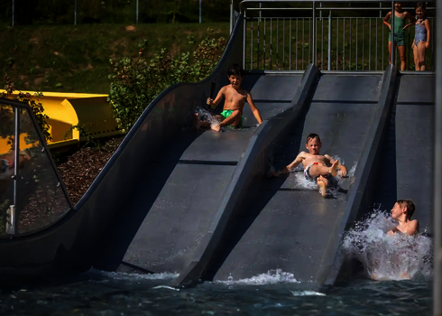 Drei Kinder rutschen zeitgleich die Trio-Slide hinab, andere warten oben.