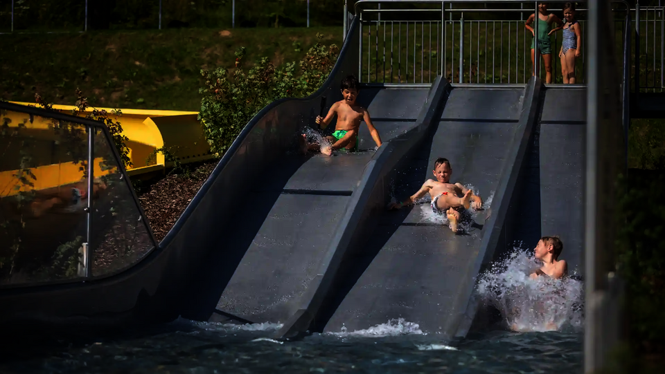 Drei Kinder rutschen zeitgleich die Trio-Slide hinab, andere warten oben.