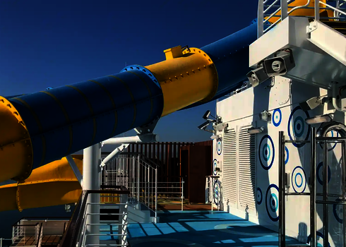 Wasserrutschen in Blau und Gelb befinden sich an Deck eines Kreuzfahrtschiffes.