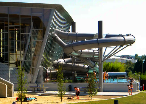 Eine graue RR1200 Wasserrutsche aus Edelstahl im Außenbereich eines Scwhimmbades.