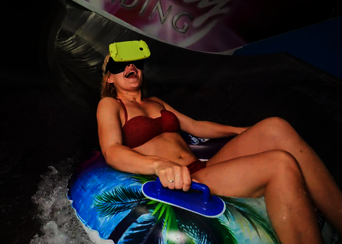 Eine Frau nutzt lachend in einem Rutschtreifen die Virtual Reality Wasserrutsche.