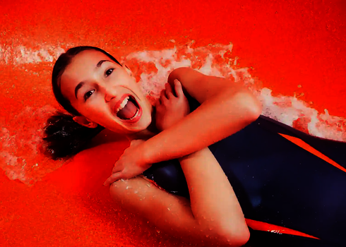 Lachendes Kind in einer roten Wasserrutsche.