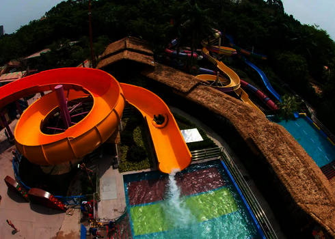 Blick von oben auf einen Wasserpark, mit Bäumen im Hintergrund.