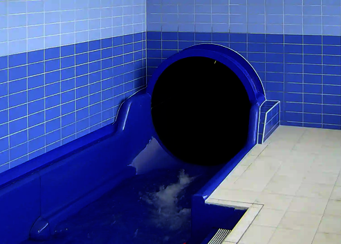 Blue slide exit with black tube entrance and light-coloured tiled interior.