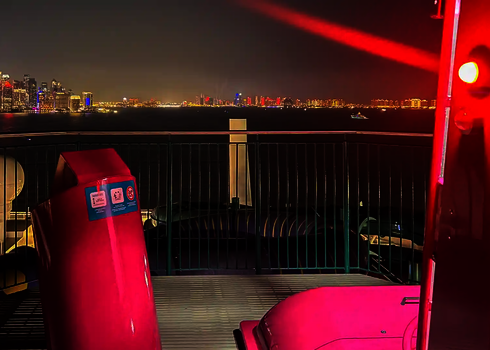 Zwei pinke U-Drop-Kapseln mit roter Sensorampel auf einem Kreuzfahrtschiff, im Hintergrund eine beleuchtete Skyline.