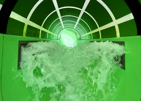 Innenansicht eines Wildwasserflusses mit Wasserdüsen und Tageslichteffekten.