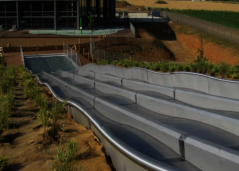 Seitliche Ansicht der Multilane im Freibad mit Wellenform und Wasserbecken.