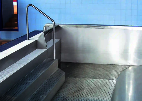 Stainless steel slide with slide and stairs leading to a shallow catch basin.