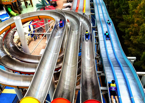 Blick von oben auf die Wasserrutsche Matracer mit offenen und geschlossenen Bahnen und Rutschern.