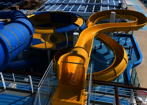 Gelbe Spiralrutsche und blaue Röhrenrutsche auf einem Kreuzfahrtschiff und in der Mitte befindet sich eine blau-gelbe Body Bowl.