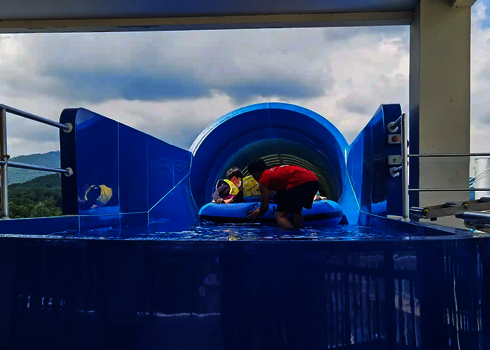 Blauer Startbereich des Urknalls, mit Sicherheitspersonal, dass Badegästen im Rutschreifen hilft.