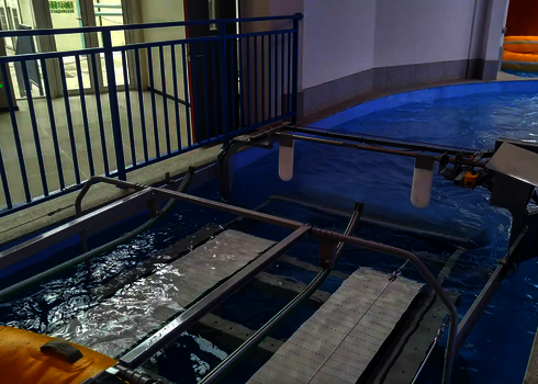 The conveyor system of the raft conveyor lifts empty inflatable boats out of the water basin.