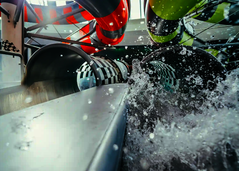 Spritzendes Wasser vor zwei Tunnelrutschen mit schwarz-weißem Schachbrettmuster.