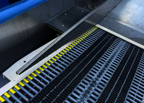 Nahaufnahme eines Gurtförderbands mit gelben Markierungen an einer Wasserrutsche.