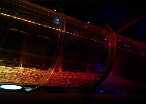 Röhrenrutsche mit orange-roten LED-Lichtern und fließendem Wasser bei Nacht.