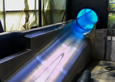 Slide landing under construction with blue tube slide and stainless steel pool.