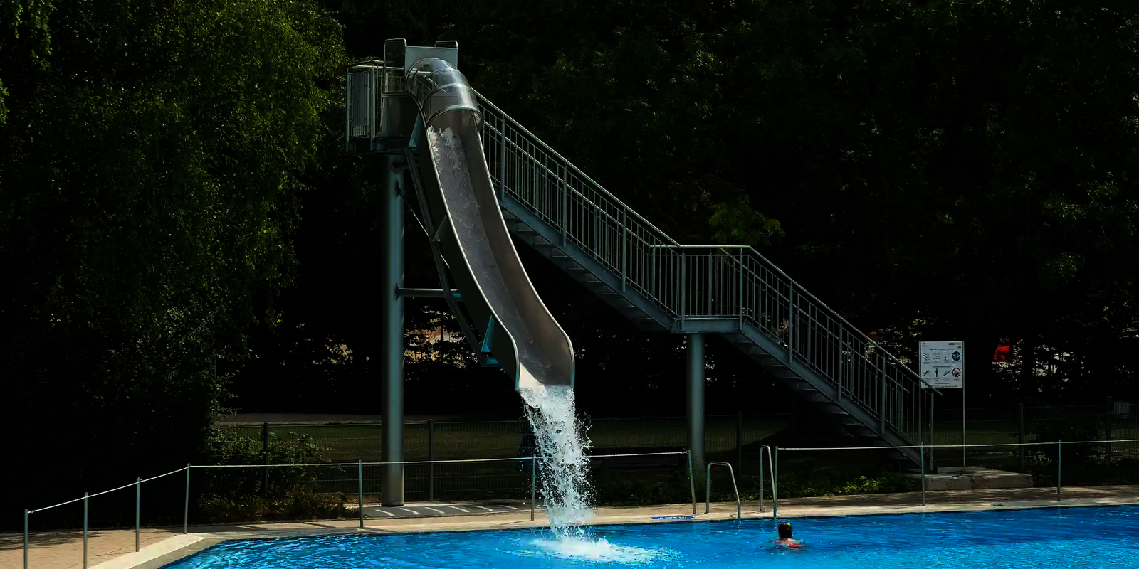 Eine Fallrutsche im Freibad endet mit einem Wasserschwall im Becken.