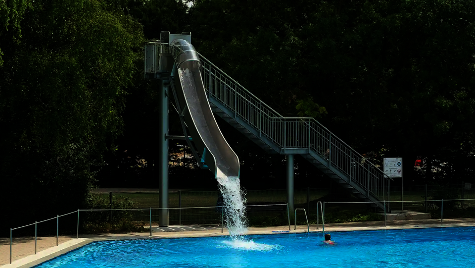 Eine Fallrutsche im Freibad endet mit einem Wasserschwall im Becken.