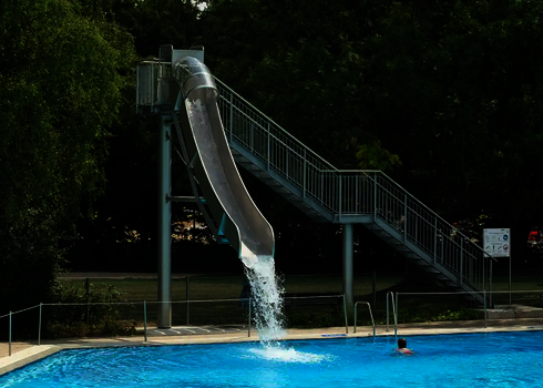 Eine Fallrutsche im Freibad endet mit einem Wasserschwall im Becken.