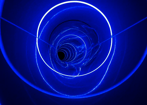 Helle LED-Ringe und Lichtreflexe in Blau verzieren die dunkle Röhrenrutsche.