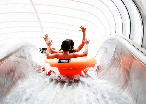 Kinder fahren in orangem Doppelreifen durch die transparente Röhre des Raft Racer.