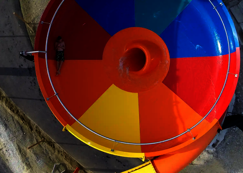Body-Bowl-Rutsche mit Mann im Zentrum auf rot-gelber Trichterfläche.
