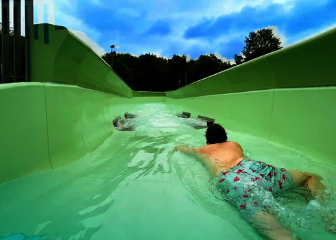 Ein Mann in Badehose rutscht bäuchlings durch den Wildwasserfluss mit Düsenantrieb.