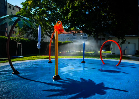 Wasserspielplatz mit Wie-Spray Elementen vor Häusern.