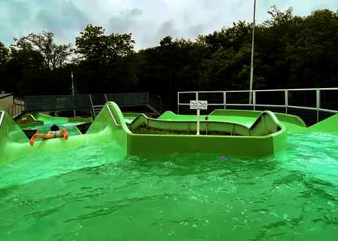 Ein Mann rutscht bäuchlings eine Gefällestrecke des Wildwasserflusses hinunter.
