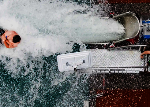 Mann in Badebekleidung rutscht aus einer Cannonball Wasserrutsche.
