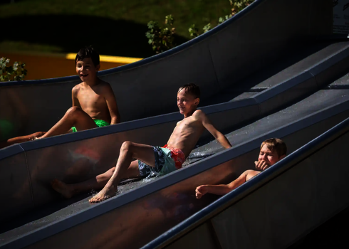 Junge hält sich beim Rutschen auf der Trio-Slide die Nase vor dem Wassereintritt.