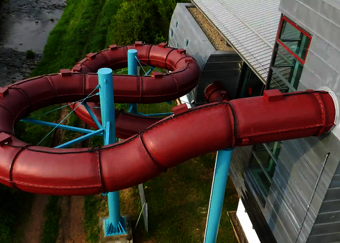 Eine rote RR1200 Wasserrutsche außerhalb eines Gebäudes mit Fassadendurchdringung.