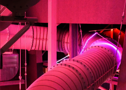 Pink beleuchtete Wasserrutsche gehalten von Drahtseilen und Stahlstützen.